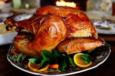 a roasted turkey on a plate with oranges and greens