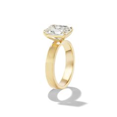 a yellow gold engagement ring with an oval cut diamond in the center, on a white background