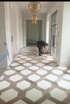 a man is working on the floor in an empty room with white and gray tiles