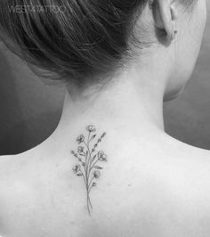 a woman's back neck with a flower tattoo on her left side ribcage