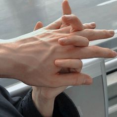 two hands reaching out towards each other on a subway car window sill, with one hand holding the other's arm