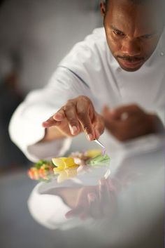 a man in a chef's uniform is preparing food on a plate with a knife and fork