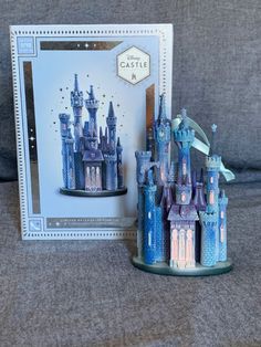 the castle is made out of plastic and sits next to a card with an ornament on it