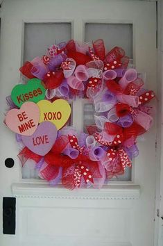 a valentine's day wreath on the front door with hearts and kisses attached to it