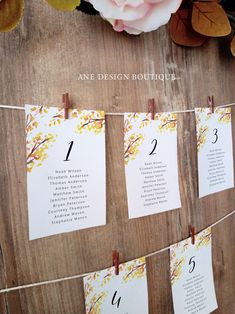 an arrangement of seating cards on a wooden table with flowers and leaves around the tables