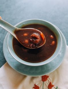 a spoon full of soup sitting on top of a blue bowl