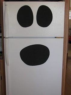 a white refrigerator with two black circles on the front and bottom door, in a kitchen