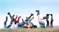 several people laying down in the grass with their legs up and feet on each other