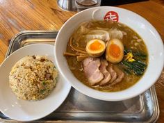 a bowl of soup with meat, rice and an egg on a tray next to a drink