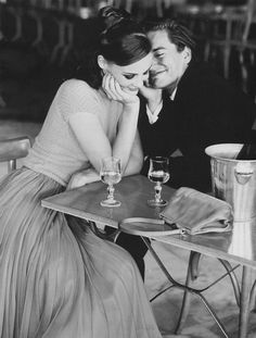 a man and woman sitting at a table with wine glasses