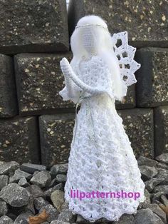 a white crocheted angel figurine sitting on some rocks