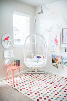 a child's room with a swing chair and bookshelf in the corner