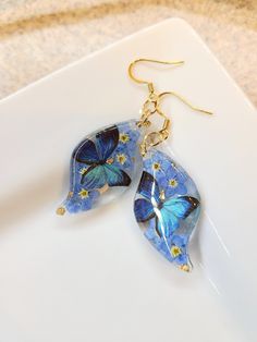 How darling are these Real Flower earrings! Perfect for yourself or for your loved ones.  The Dangles are made with real pressed forget me not flowers and Cerulean Butterflies with a hint of gold flakes.  All Jewelry findings are Nickel and Lead Free. The petals and ferns have been carefully preserved to retain their color and would make a great gift for your loved ones. This piece was made with real flowers and hence it is important to preserve the jewelry in the box provided safely away from direct sunlight.  You can see more of my Handmade Items here:  https://www.etsy.com/shop/Thecraftiechristie Whimsical Blue Flower Earrings For Gift, Dangle Flower Earrings As Gift, Dangle Flower Earrings With Ear Wire As A Gift, Artistic Flower Earrings For Gifts, Unique Flower Earrings For Pierced Ears As Gift, Whimsical Teardrop Earrings For Pierced Ears, Whimsical Teardrop Jewelry For Pierced Ears, Artistic Flower Drop Earrings For Gift, Artistic Drop Flower Earrings As Gift