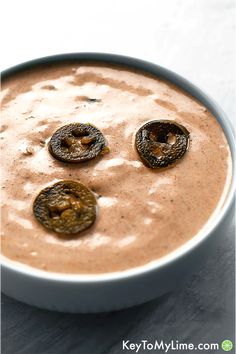 a bowl filled with some kind of food on top of a white countertop next to a cup of coffee