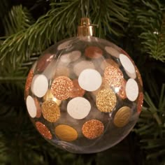 a christmas ornament hanging from a tree with gold and white dots on it