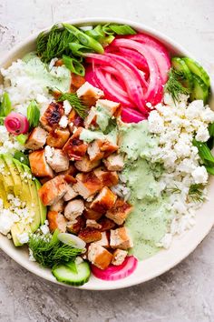 a white bowl filled with meat, vegetables and rice on top of a gray surface