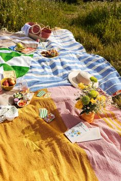 a picnic blanket is laid out on the grass with food and flowers in vases