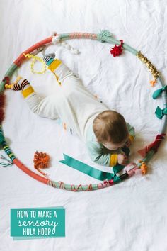 a baby laying on top of a hula hoop surrounded by beads and tassels