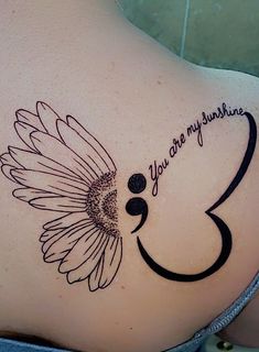 a woman's back with a tattoo that reads, you are my sunshine and a flower