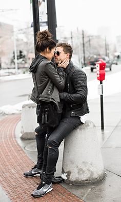 a man and woman sitting on top of a cement pillar next to a red fire hydrant