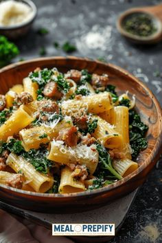 a bowl filled with pasta and spinach on top of a black table next to other dishes