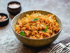 a close up of a bowl of food on a table next to a fork and spoon