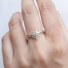 a woman's hand wearing a gold ring with two diamonds on it and the middle finger