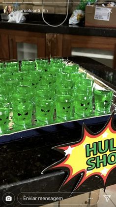 there are many green cups that have been placed in the middle of a counter top