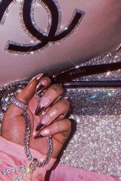 a woman's hand with pink manicures holding onto a chanel bag