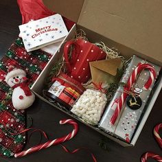 an open christmas gift box filled with candy canes, marshmallows and candies