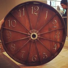 a person holding a large wooden clock with numbers on it