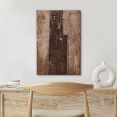 an abstract painting hangs on the wall above a wooden table