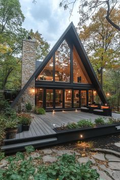 a - frame house in the woods surrounded by greenery and stone walls, with an outdoor deck