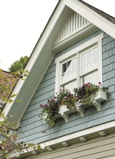 two window boxes with flowers in them on the side of a house's roof