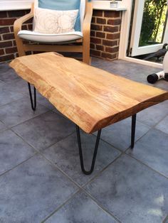 a wooden table sitting on top of a tile floor next to a chair and window