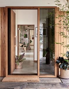 an open door leading into a room with potted plants on the outside and inside