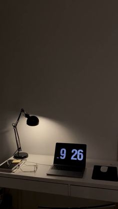 a laptop computer sitting on top of a desk next to a lamp and a clock