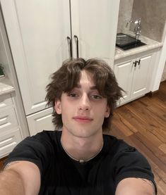 a young man sitting on the floor in front of a kitchen sink and counter top