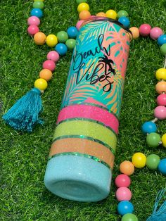 a colorful tube laying on top of green grass next to beads and tassels