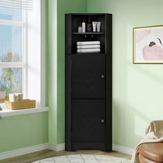 a bathroom with green walls and a black cabinet in the corner next to a window