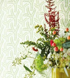 a vase filled with lots of flowers on top of a table next to a wall