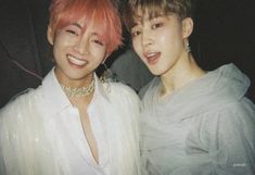 two young men standing next to each other with pink hair and piercings on their ears