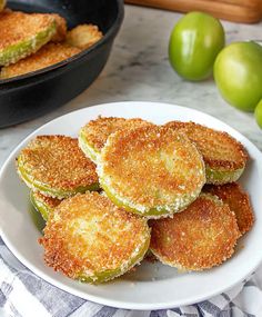 some fried food on a white plate next to green apples