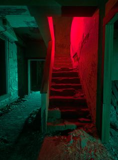 an abandoned building with red light coming from the top and stairs leading up to it