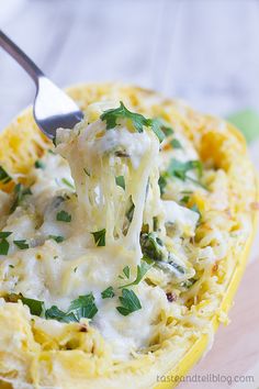 a spoon is lifting some food out of the casserole dish with broccoli and cheese