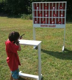 a little boy standing in front of a sign holding a cell phone to his ear