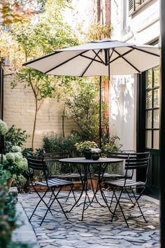 Outdoor patio with a round table, four chairs, and an umbrella in a garden setting. Patio Deck Decorating Ideas, Small Patio Designs, Townhome Patio, Marble Patio, Patio Ideas On A Budget, Striped Furniture, Patio Upgrade, Small Patio Design, European Cafe