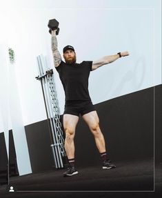 a man in black shirt and shorts standing on stage with his arms raised above his head