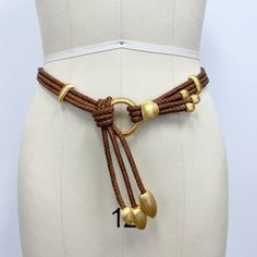 a white mannequin wearing a brown belt with gold beads