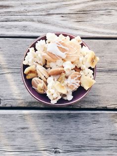 a bowl filled with bananas and nuts on top of a wooden table